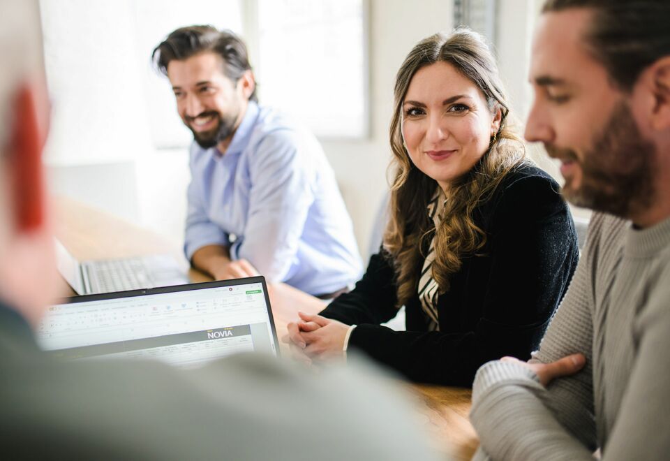 NOVIA GmbH Consulting und Baumanagement - Teammeeting: Mitarbeiterin schaut zugewandt in Kamera