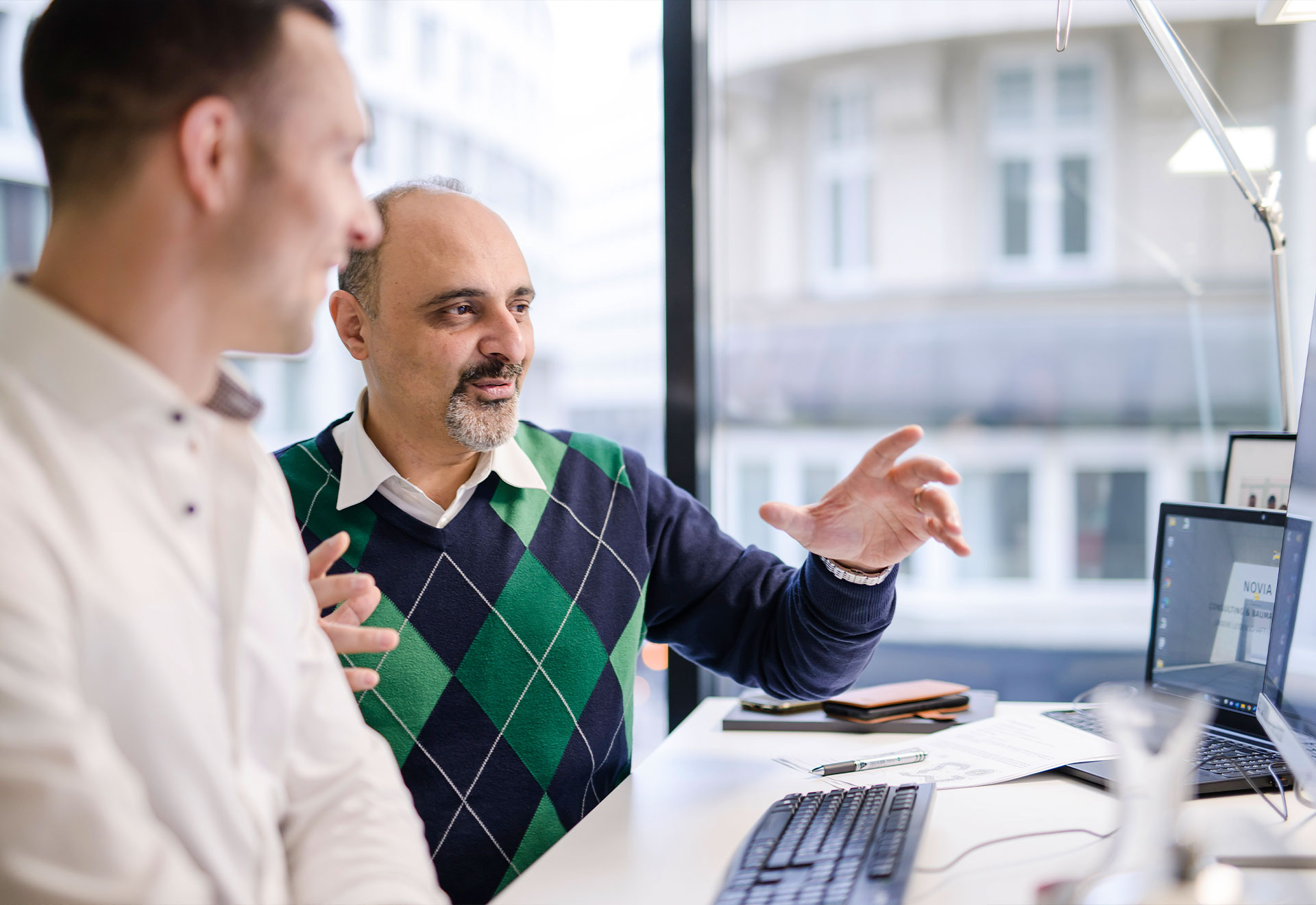 NOVIA GmbH Consulting und Baumanagement - Mitarbeiter erklärt Kollegen am Platz den Status zum Projekt